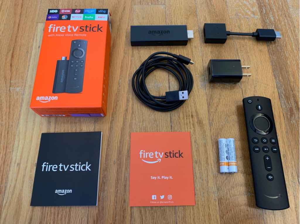 streaming tv stick, cords, box, batteries, and instructions laid out on wooden table